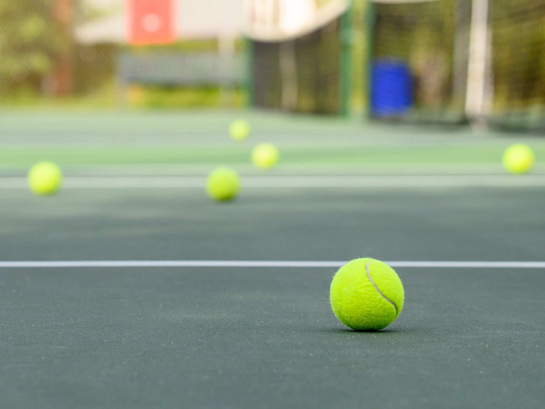 Mehrere gelbe Tennisbälle auf einem Tennisplatz.